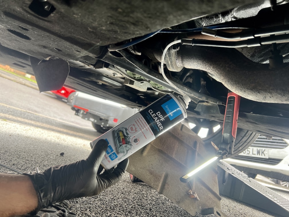 DPF cleaner being applied to a diesel particulate filter underneath a vehicle