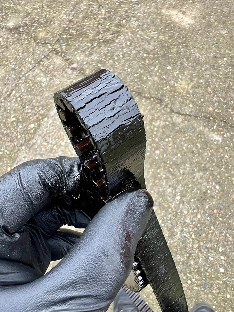 Worn and oil-soaked timing belt removed from a vehicle engine